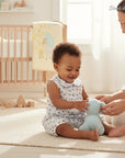 Stork And Baby white floral print romper with collar on a baby girl playing with a blue toy.