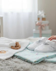 Stork And Baby white christening booties for girls featuring delicate heart embroidery and a soft bow detail.
