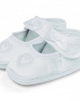 Stork And Baby white satin christening booties for girls featuring embroidered heart detail and a delicate bow strap.