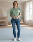 Stork And Baby green muslin wrap top with embroidered dinosaurs and button closure. Short sleeves, perfect for summer.