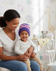 Stork And Baby purple and pink striped knit infants winter hat on a smiling baby.