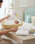 Stork And Baby Mothers Choice cotton jersey baby wrap in a nursery setting with a swaddled newborn in a basket