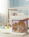 Stork And Baby Mothers Choice pink infants cutwork blanket with bear design in clear gift packaging in a nursery.