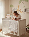 Stork And Baby Mothers Choice white cotton jersey baby wrap draped over a crib with a mother and newborn inside.