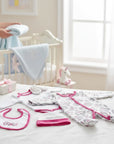 Stork And Baby 5-piece newborn "I'M Fancy" starter pack: onesie, bib, hat, mittens, and blanket. White cotton with pink trim and floral print.