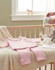 Stork And Baby pink quilted 2-piece baby girl set with ruffled collar and bow accents on leggings.