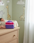 Stork And Baby striped knit baby hat in purple, pink, and magenta. Cozy winter accessory for infants.
