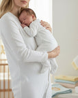 Stork And Baby white cotton babygrow with footies, held by a mother. Soft and breathable for newborns.
