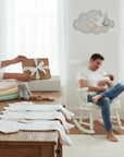 Stork And Baby white 100% cotton babygrows for premature babies, laid out on a wooden table.