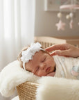 Stork And Baby white satin and lace alice band with polka dot bow on a sleeping newborn baby in a nursery basket