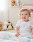 Stork And Baby white girls Alice band featuring delicate pearls and beads, worn by a smiling baby in a nursery.