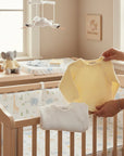 Stork And Baby yellow knit baby cardigan with white trim and buttons, shown with a white cardigan.